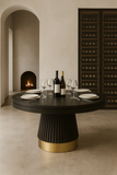 Black dining table with wine bottles and glasses in a room with a fireplace and wine rack.