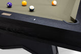 Close-up of a pool table corner with a dark wood frame, green felt surface, and several billiard balls including a purple 9-ball, yellow 8-ball, blue 7-ball, and orange/white 6-ball.