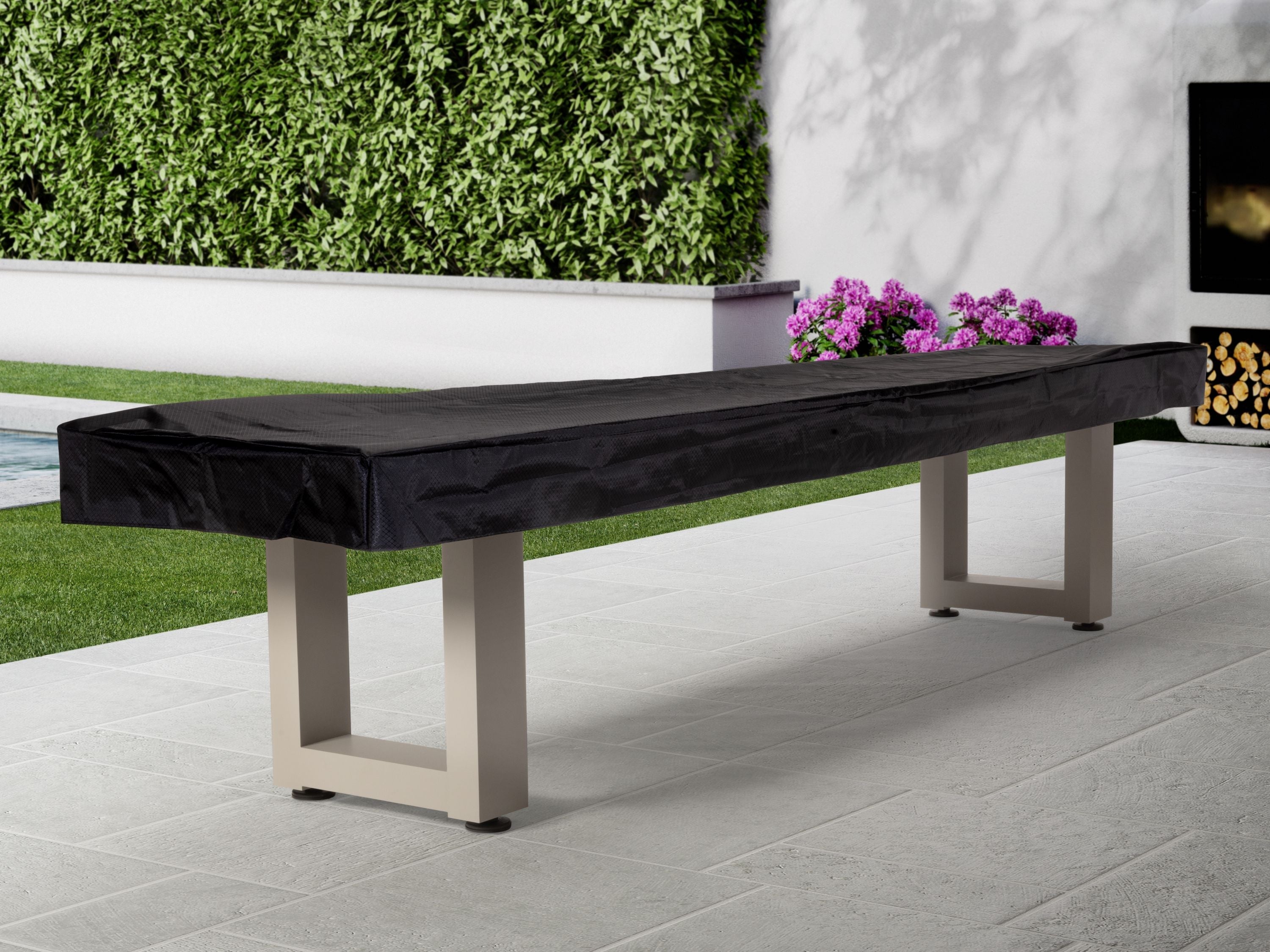 American Heritage Lanai 12' Oyster Grey shuffleboard table on patio near greenery and flowers.