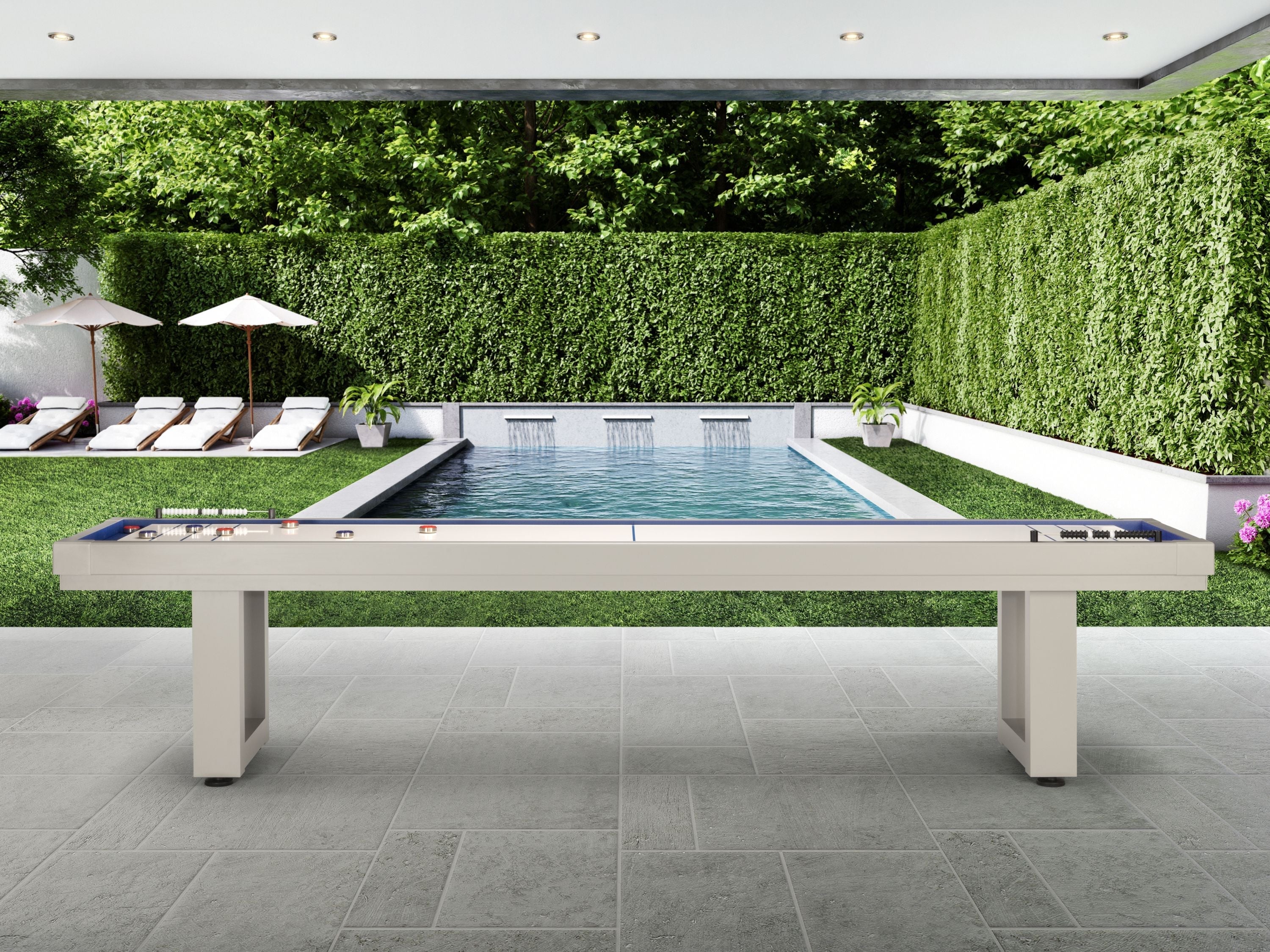 American Heritage Lanai 12' Outdoor Shuffleboard Table in Oyster Grey overlooks pool and chairs.