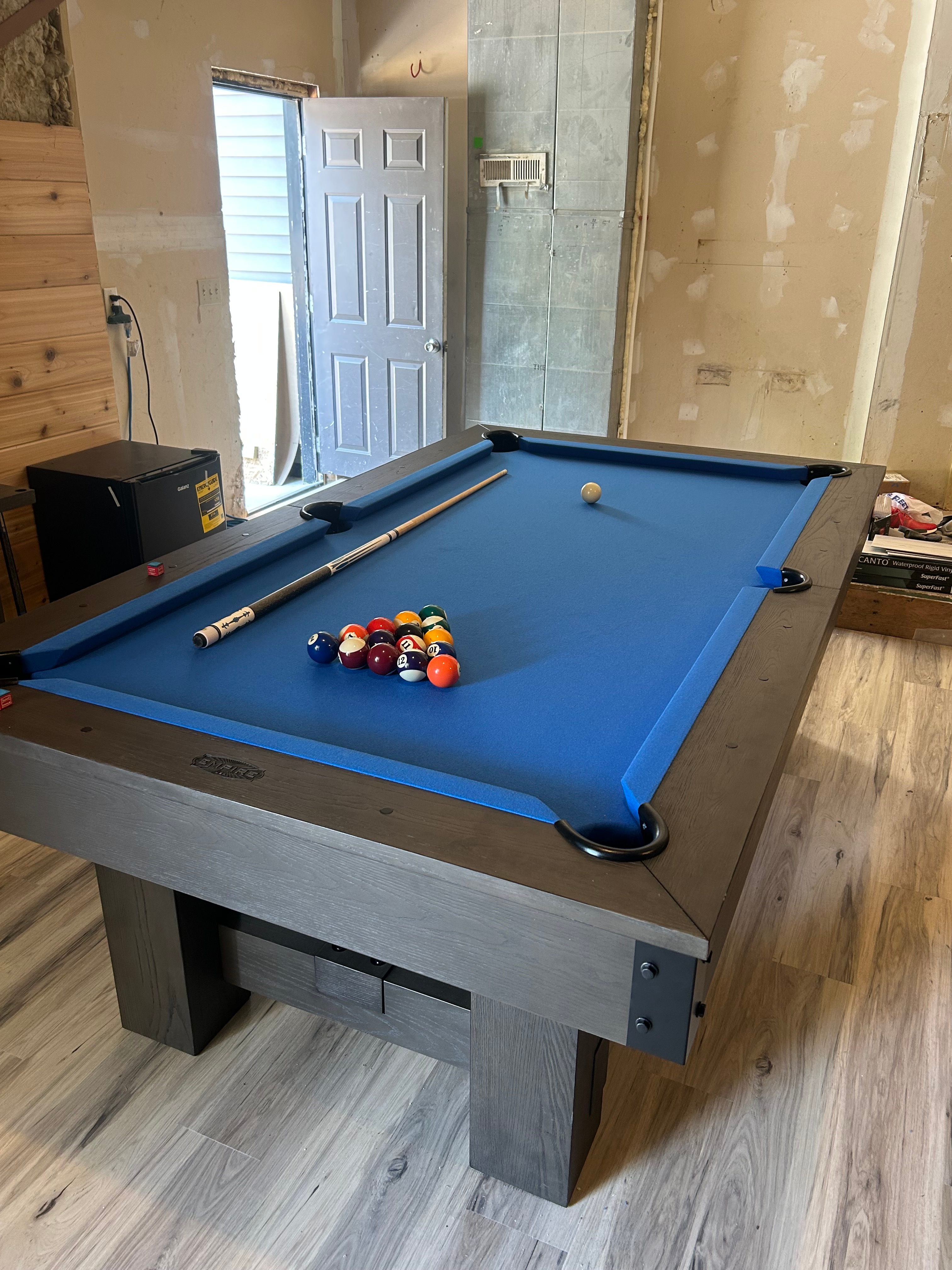 Pool table with blue felt and billiard balls in a room under renovation.