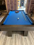 Pool table with blue felt and pool balls in a room with construction materials.