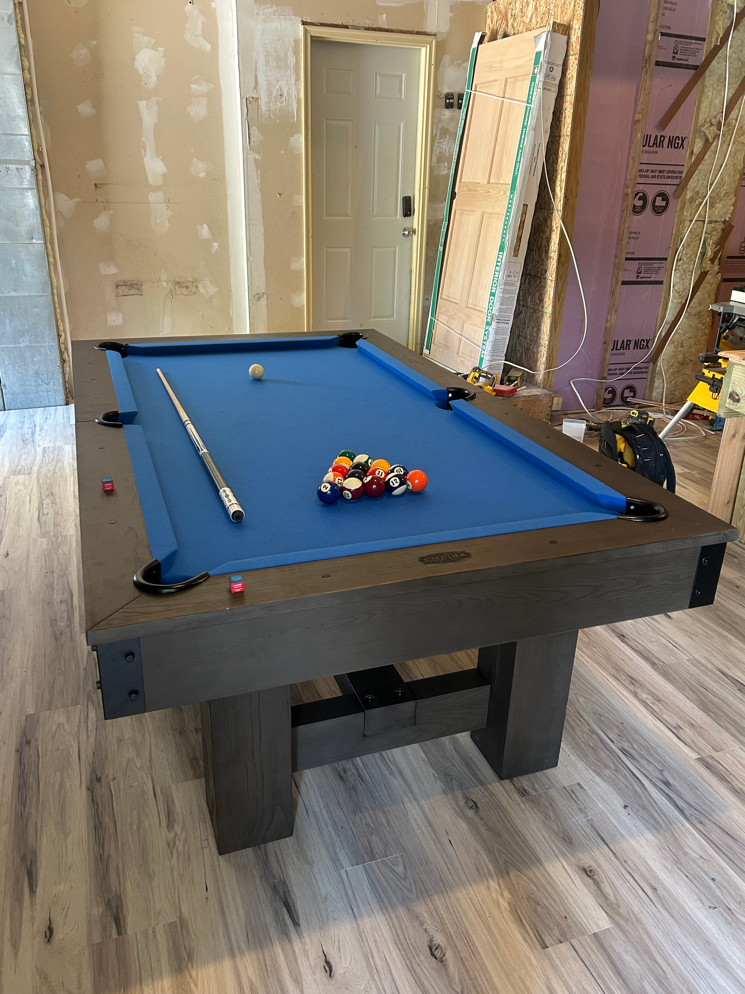 Pool table with blue felt and billiard balls in a room under renovation.