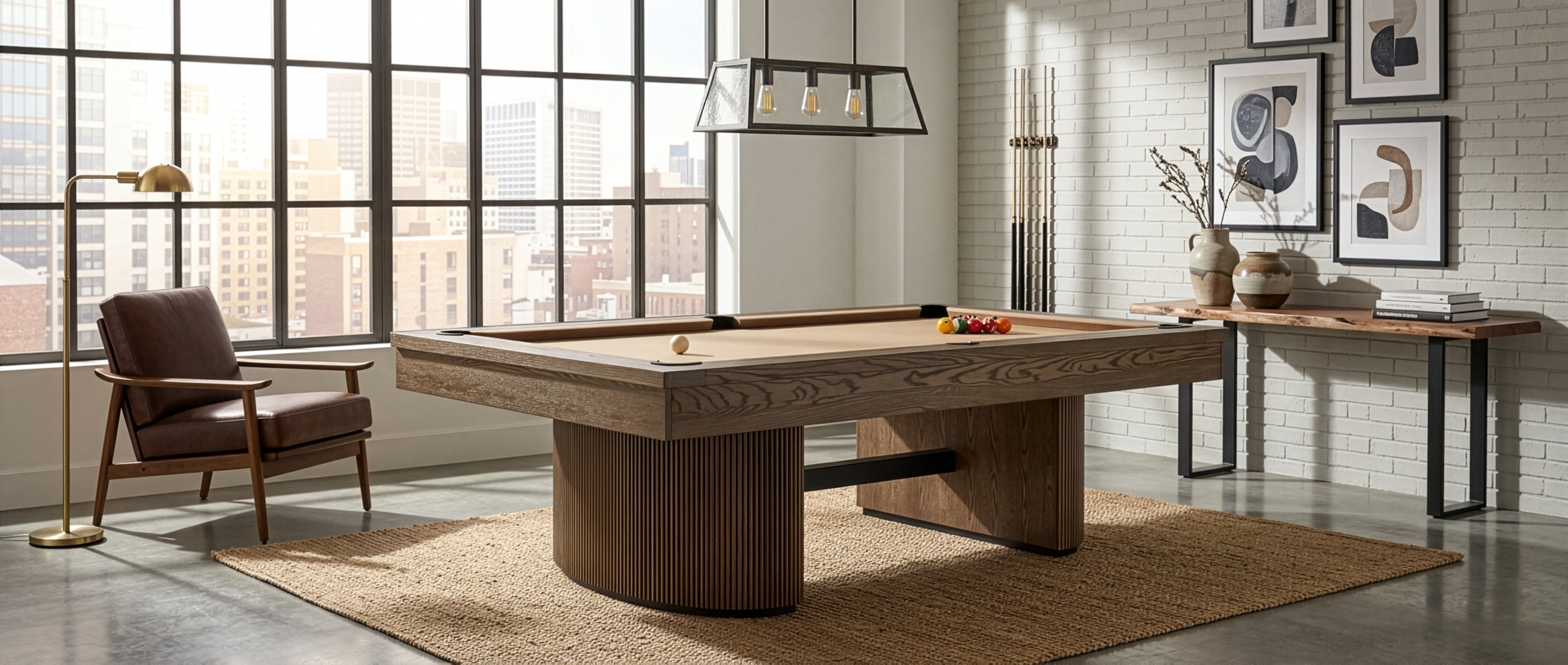 A modern wooden pool table in a bright, contemporary loft room with large industrial windows, a brown leather armchair, and a white brick wall.