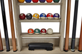 Pool balls on a wooden shelf with pool cues on either side.